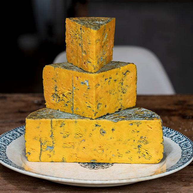 Whole Blacksticks Blue Cheese, a 2.5kg cheese wheel sliced up and presented in large portions on top of one another. Available from Butlers Farmhouse Cheeses