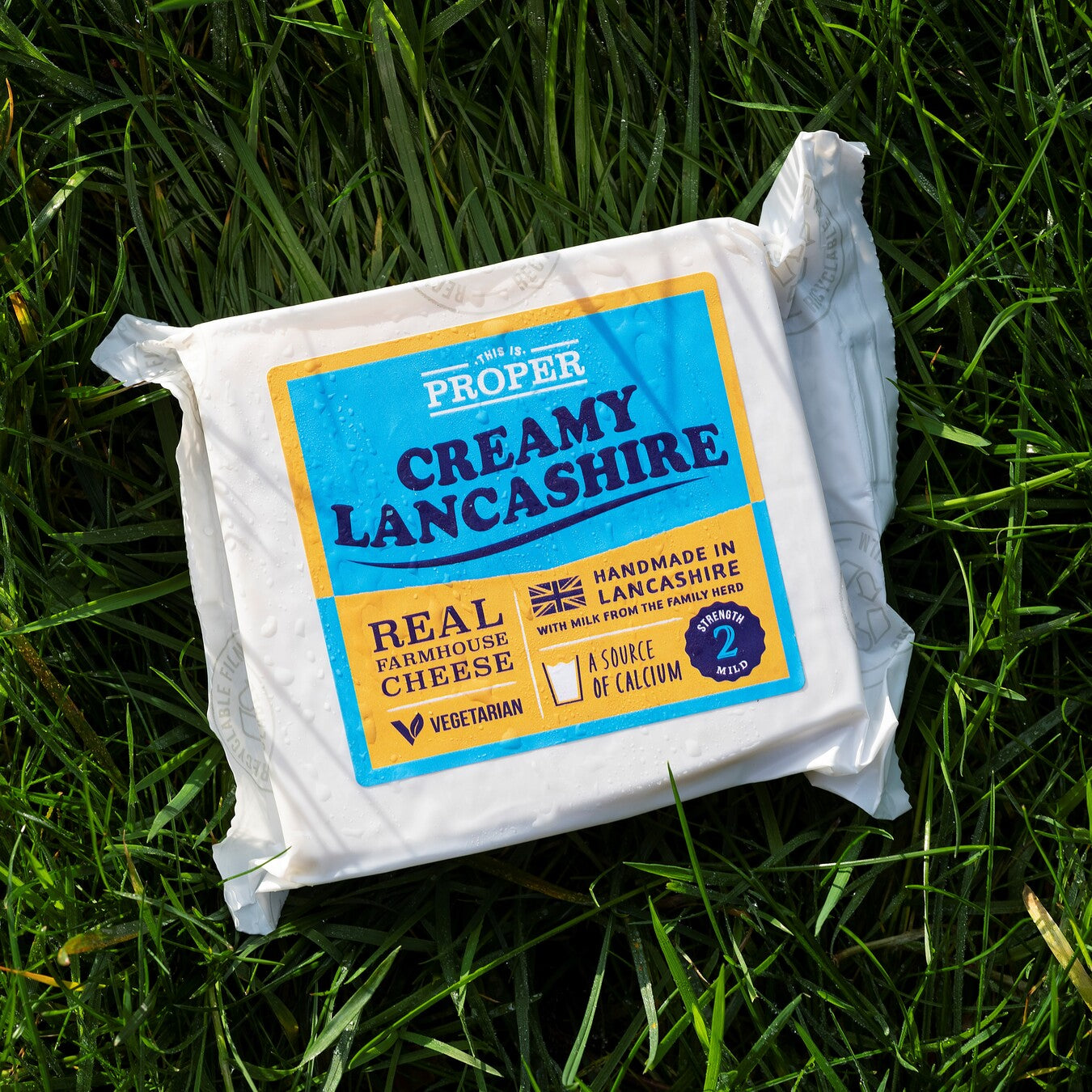 This is Proper Creamy Lancashire cheese packet resting outside on the grass.